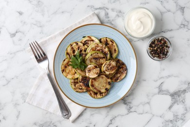 Photo of Tasty grilled courgette slices with parsley served on white marble table, flat lay