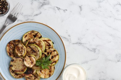 Photo of Tasty grilled courgette slices served on white marble table, flat lay. Space for text