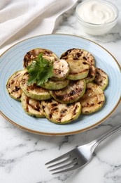 Photo of Tasty grilled zucchini slices with parsley served on white marble table