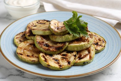 Photo of Tasty grilled zucchini slices with parsley on white marble table, closeup