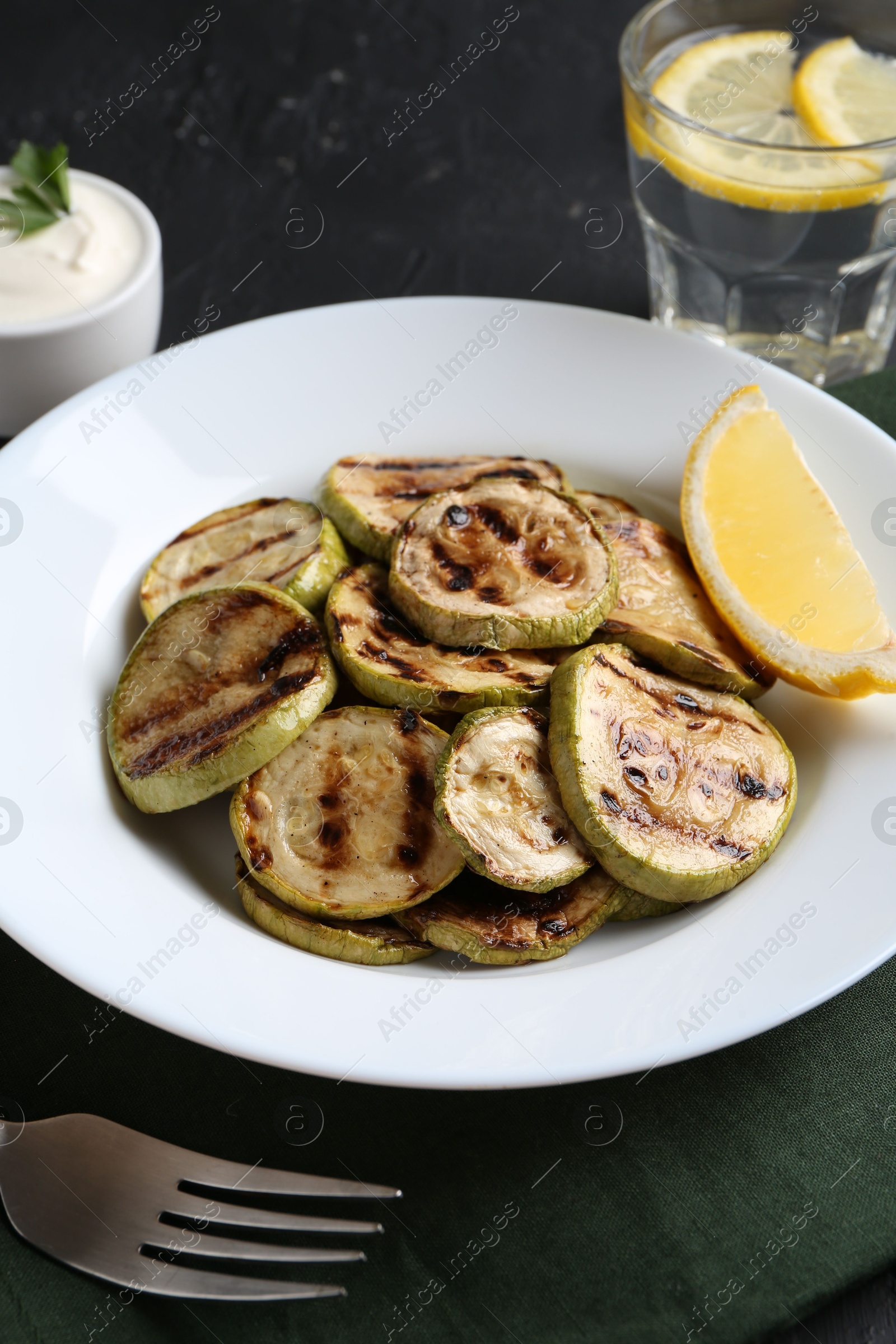 Photo of Tasty grilled zucchini slices served on black table