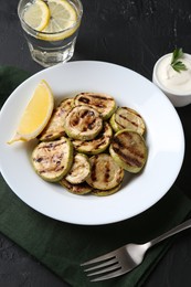 Photo of Tasty grilled zucchini slices served on black table, above view