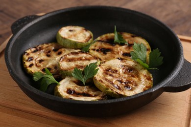 Photo of Tasty grilled zucchini slices with parsley in dish on table, closeup