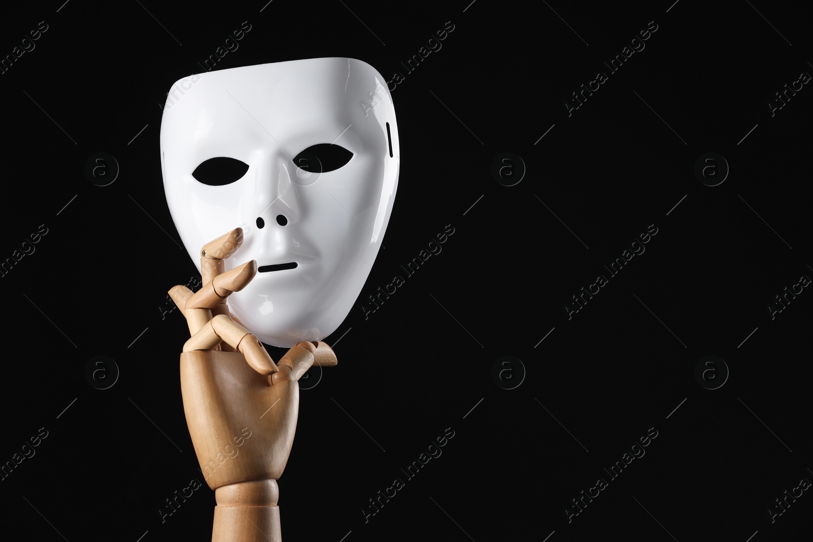 Photo of Wooden mannequin hand holding plastic mask on black background, space for text. Theatrical performance