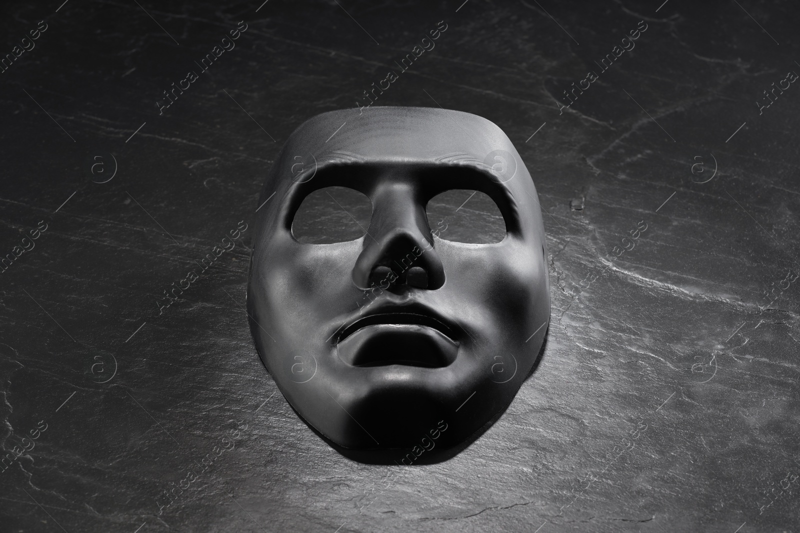 Photo of Plastic face mask on black slate surface, space for text. Theatrical performance