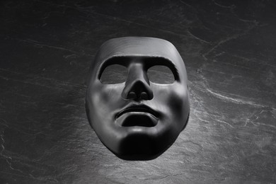 Plastic face mask on black slate surface, space for text. Theatrical performance