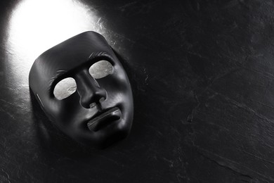 Photo of Plastic face mask on black slate surface, top view and space for text. Theatrical performance