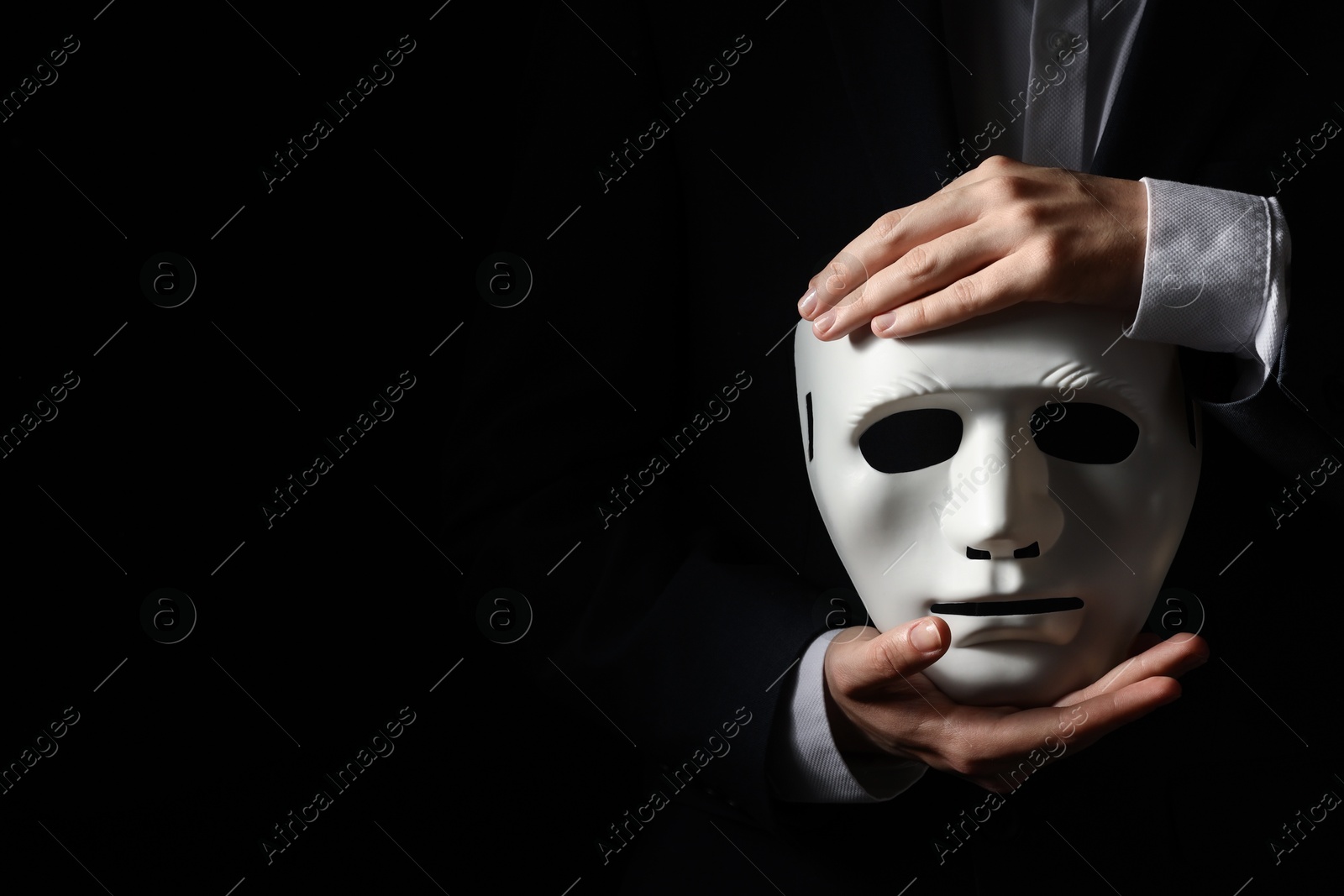 Photo of Theatrical performance. Man holding plastic mask on black background, closeup. Space for text