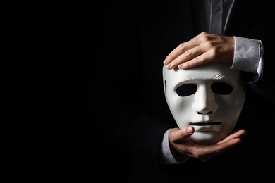 Theatrical performance. Man holding plastic mask on black background, closeup. Space for text