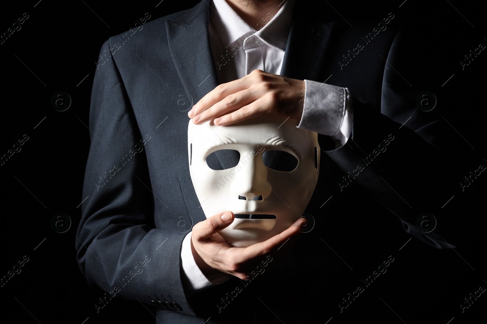 Photo of Theatrical performance. Man holding plastic mask on black background, closeup