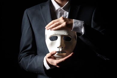 Theatrical performance. Man holding plastic mask on black background, closeup