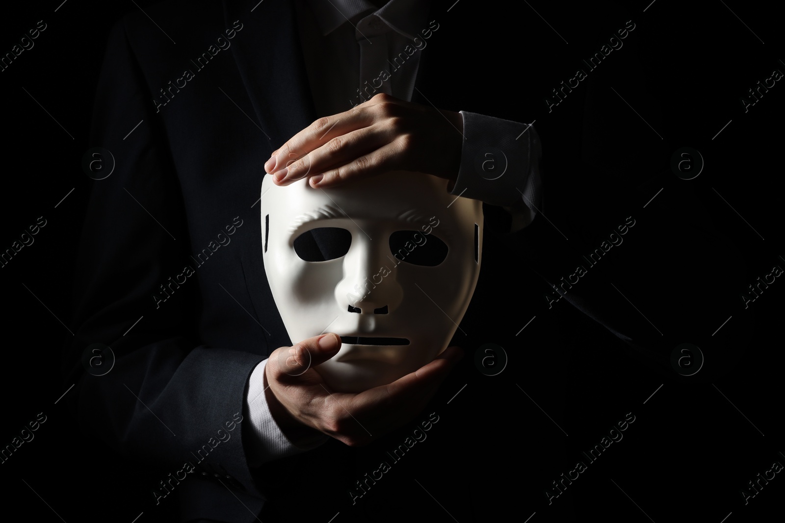 Photo of Theatrical performance. Man holding plastic mask on black background, closeup