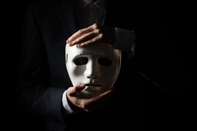 Theatrical performance. Man holding plastic mask on black background, closeup