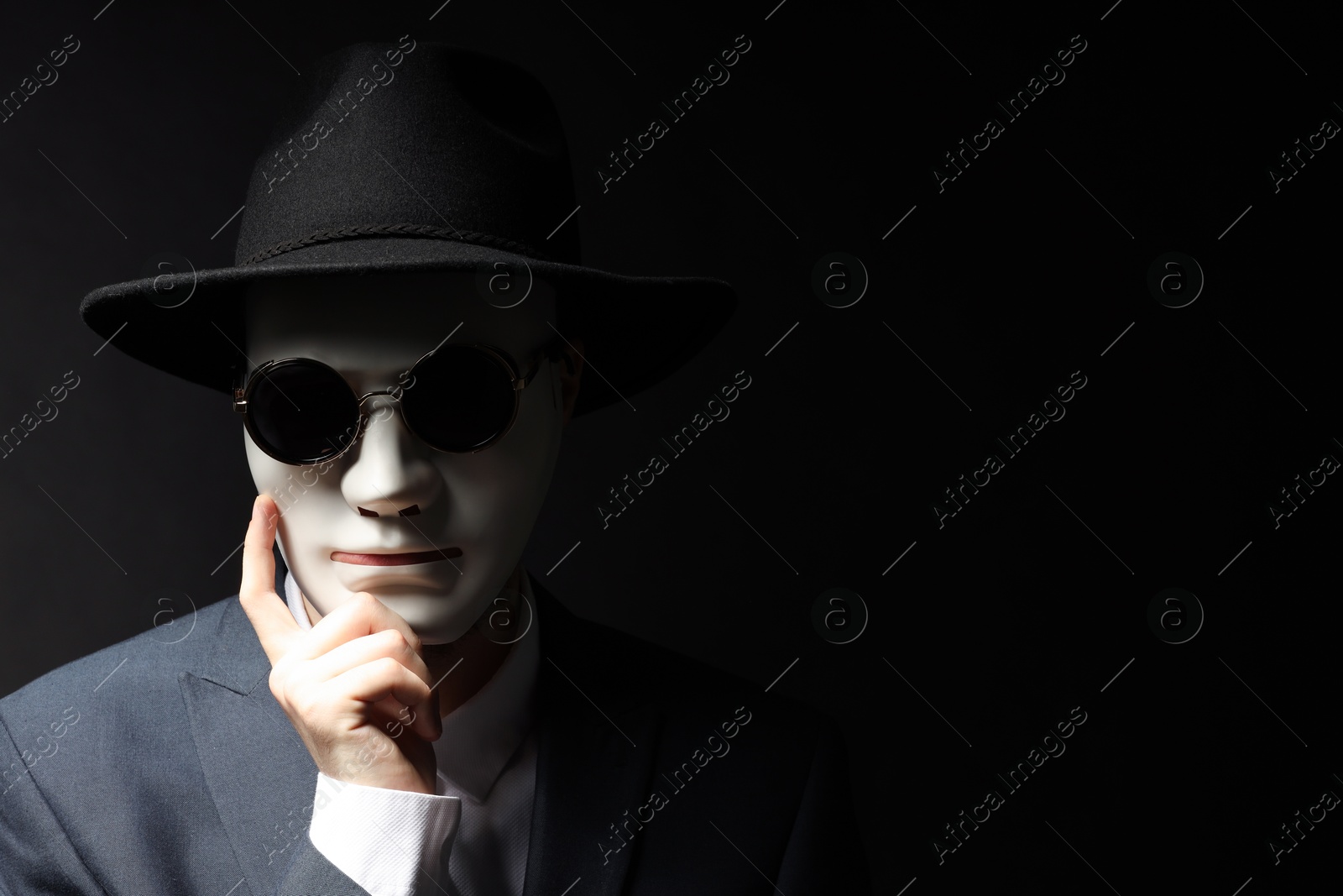 Photo of Theatrical performance. Man with plastic mask and sunglasses on black background, space for text