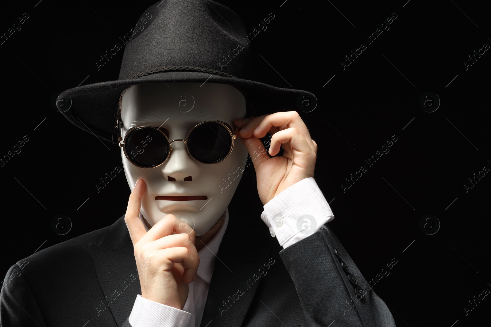 Photo of Theatrical performance. Man with plastic mask and sunglasses on black background