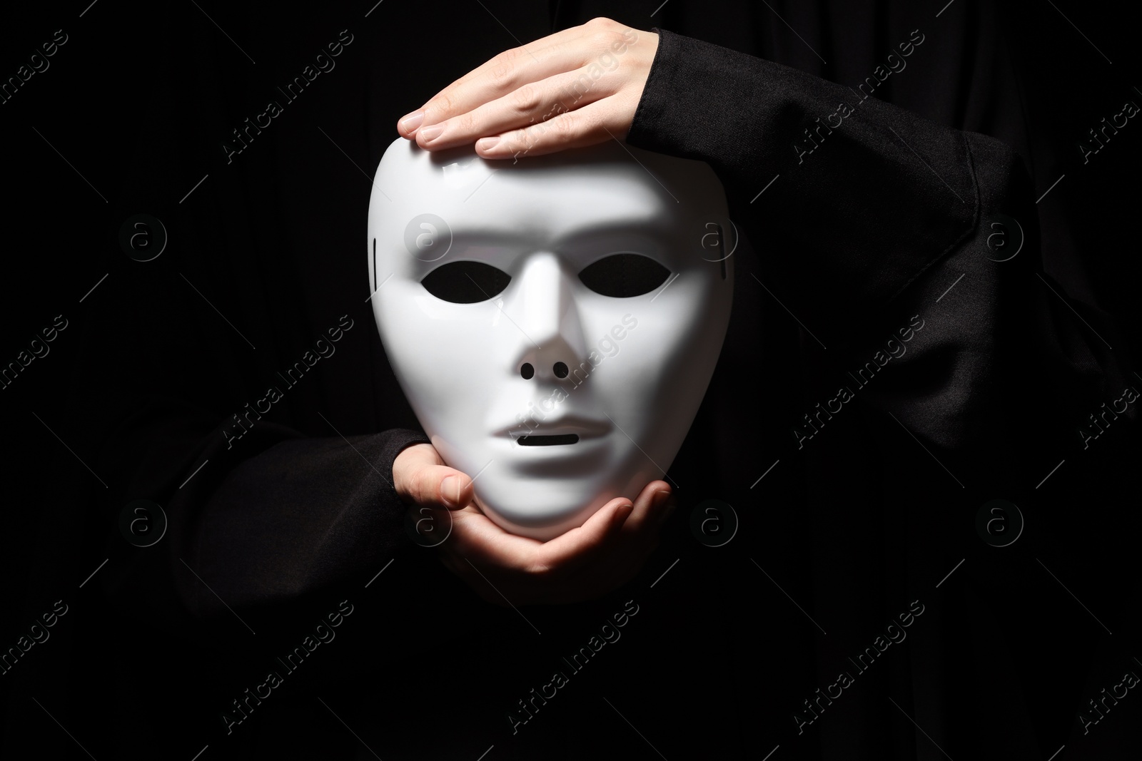 Photo of Theatrical performance. Man holding plastic mask on black background, closeup