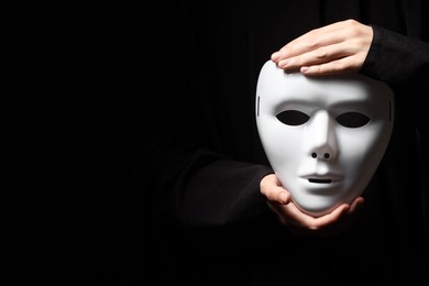 Theatrical performance. Man holding plastic mask on black background, closeup. Space for text