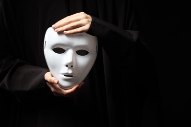 Photo of Theatrical performance. Man holding plastic mask on black background, closeup