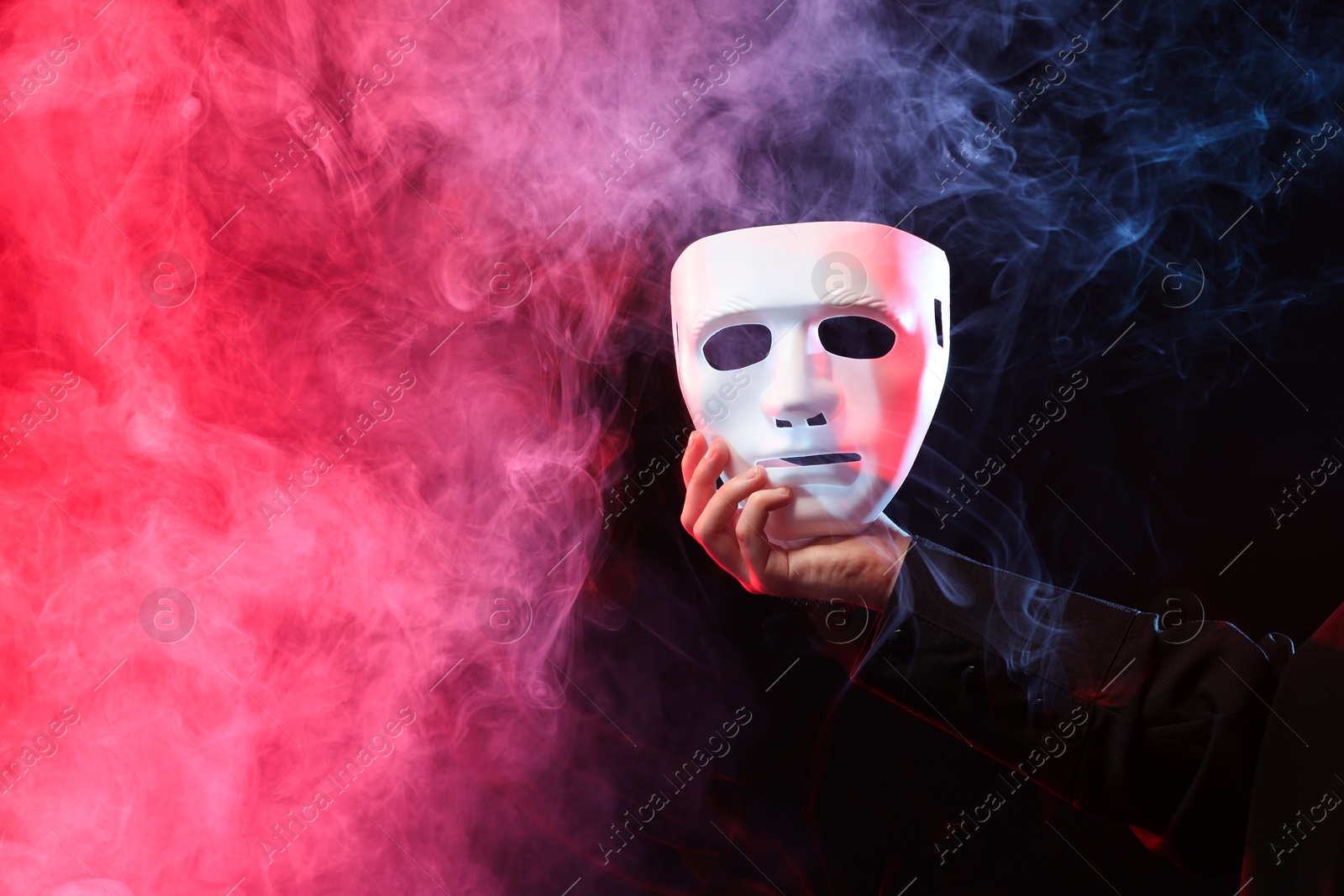 Photo of Theatrical performance. Man with plastic mask in smoke on dark background, closeup. Space for text