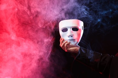 Photo of Theatrical performance. Man with plastic mask in smoke on dark background, closeup. Space for text