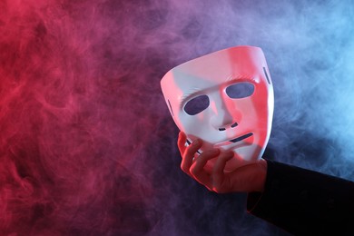 Theatrical performance. Man with plastic mask in smoke on dark background, closeup. Space for text