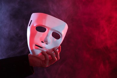 Theatrical performance. Man with plastic mask in smoke on dark background, closeup. Space for text