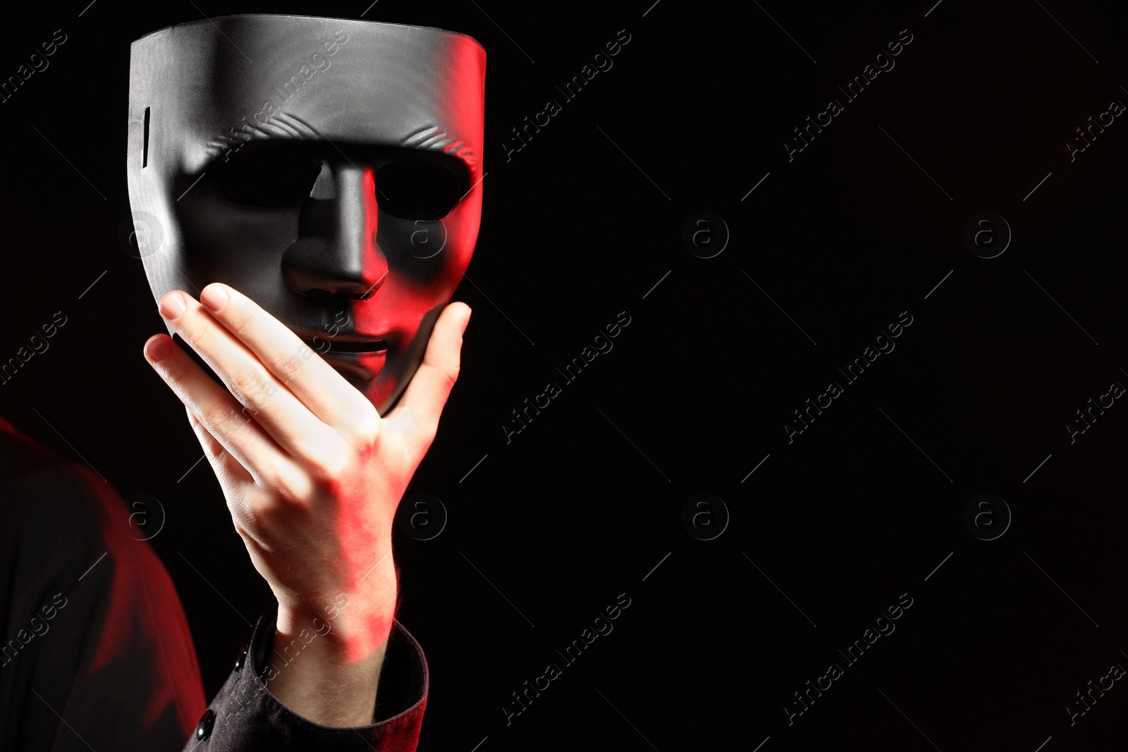 Photo of Theatrical performance. Man with plastic mask on dark background, closeup. Space for text