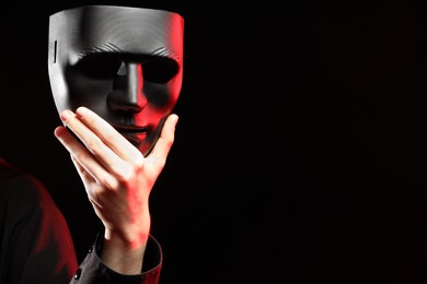 Theatrical performance. Man with plastic mask on dark background, closeup. Space for text