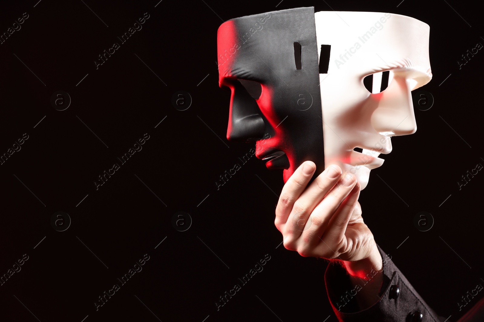 Photo of Theatrical performance. Man with plastic masks on dark background, closeup, space for text