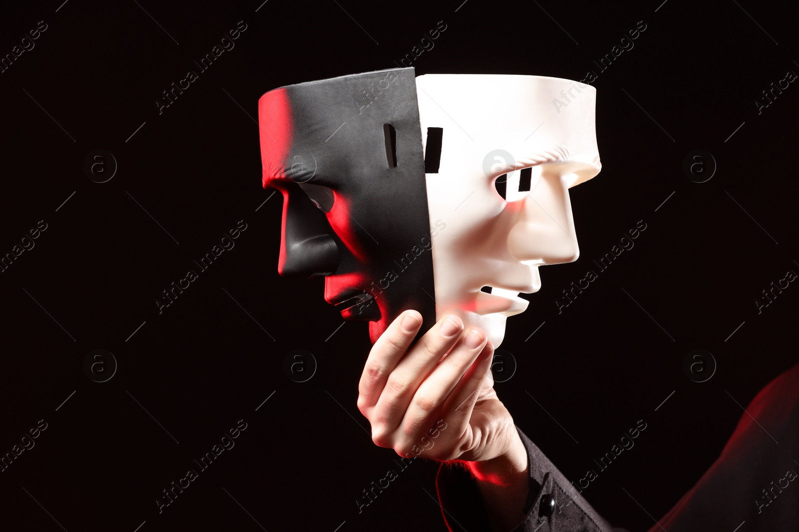 Photo of Theatrical performance. Man with plastic masks on dark background, closeup