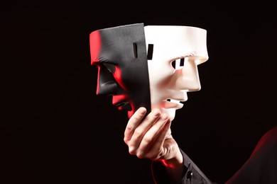 Photo of Theatrical performance. Man with plastic masks on dark background, closeup