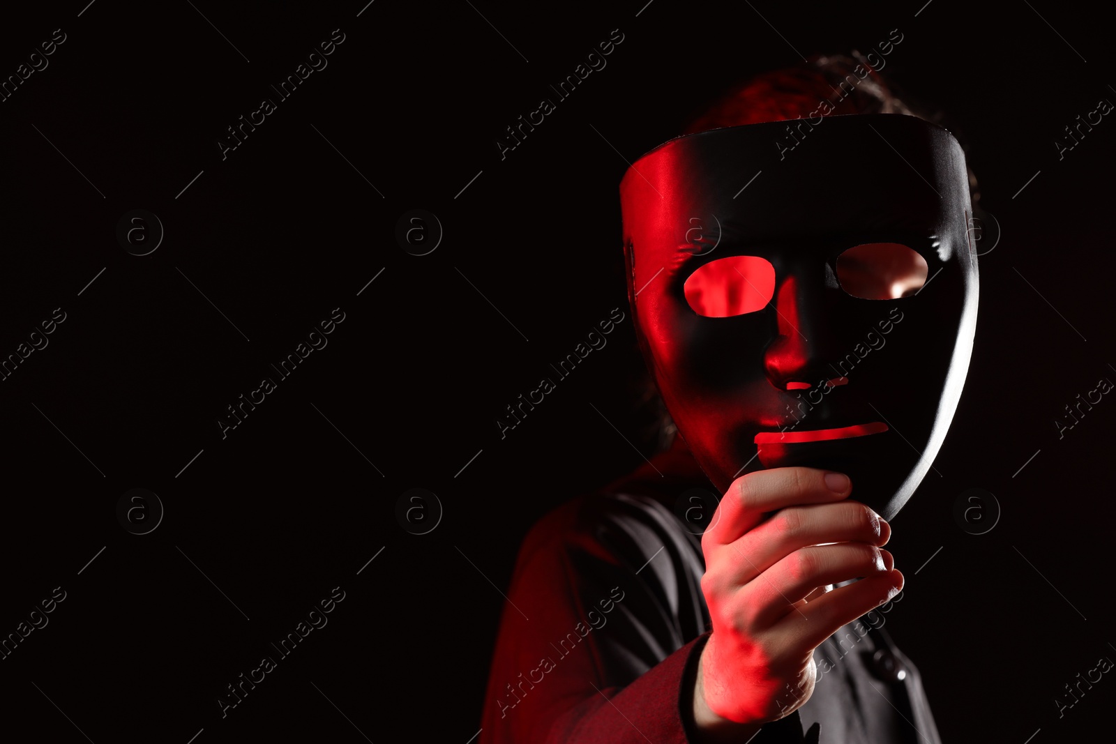 Photo of Theatrical performance. Man with plastic mask on dark background, space for text