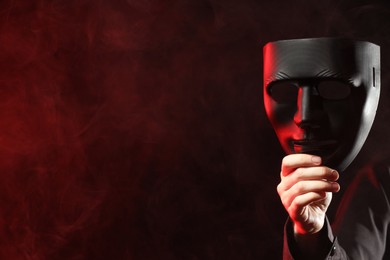 Photo of Theatrical performance. Man with plastic mask in smoke on dark background, closeup. Space for text