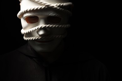 Theatrical performance. Man with plastic mask and hemp rope on black background, space for text