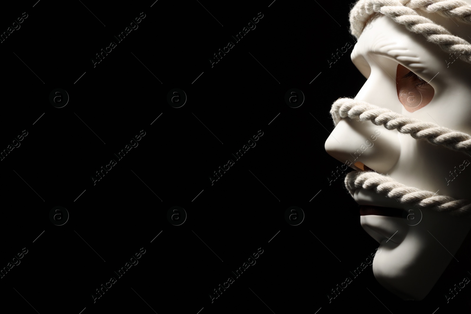 Photo of Theatrical performance. Man with plastic mask and hemp rope on black background, space for text