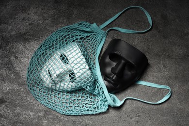 Photo of Theatrical performance. Plastic masks and string bag on grey table, top view