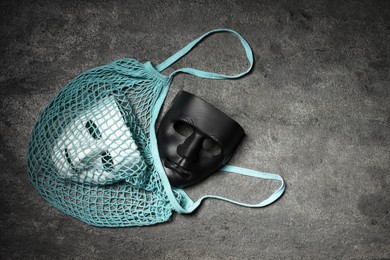 Photo of Theatrical performance. Plastic masks and string bag on grey table, top view. Space for text