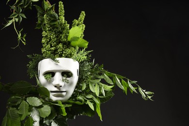 Photo of Theatrical performance. Plastic mask and floral decor on black background