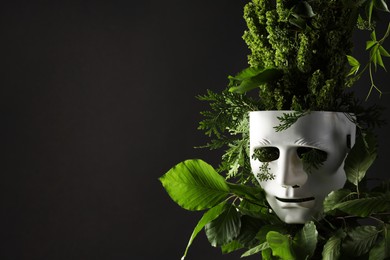 Photo of Theatrical performance. Plastic mask and floral decor on black background, space for text