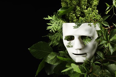 Photo of Theatrical performance. Plastic mask and floral decor on black background, space for text