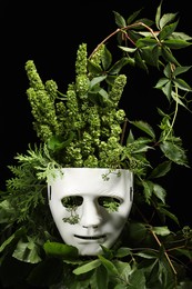 Photo of Theatrical performance. Plastic mask and floral decor on black background