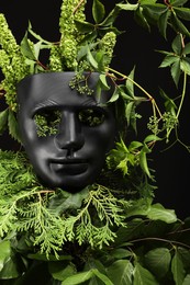 Photo of Theatrical performance. Plastic mask and floral decor on black background