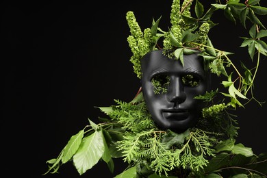 Photo of Theatrical performance. Plastic mask and floral decor on black background, space for text