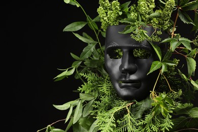 Photo of Theatrical performance. Plastic mask and floral decor on black background, space for text