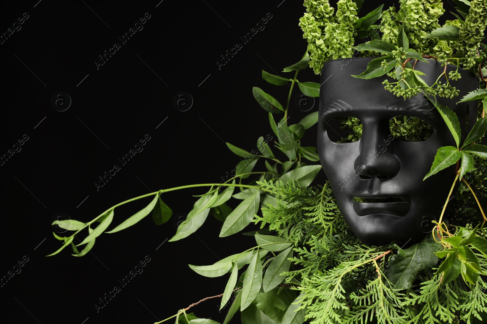 Photo of Theatrical performance. Plastic mask and floral decor on black background, space for text