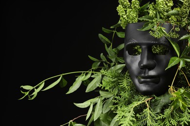 Photo of Theatrical performance. Plastic mask and floral decor on black background, space for text