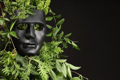 Photo of Theatrical performance. Plastic mask and floral decor on black background, space for text