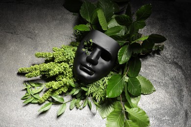 Photo of Theatrical performance. Plastic mask and floral decor on grey table