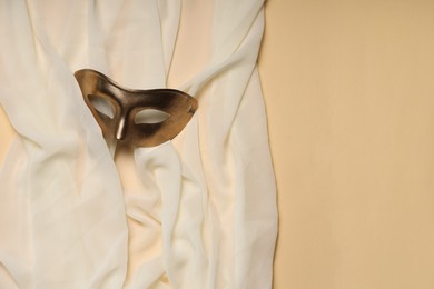 Photo of Theatrical performance. Elegant face mask and white fabric on beige background, top view. Space for text