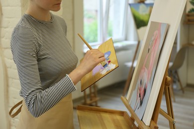 Photo of Woman drawing picture with brush in studio, closeup